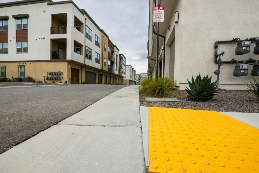 DOT-compliant sidewalk replacement site with safety barriers near an apartment building in NYC.