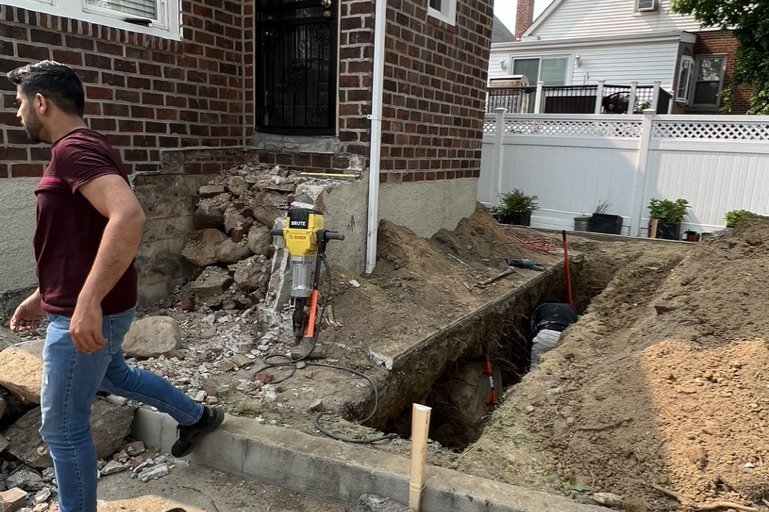Crew breaking up old damaged concrete at a NYC property before a sidewalk repair
